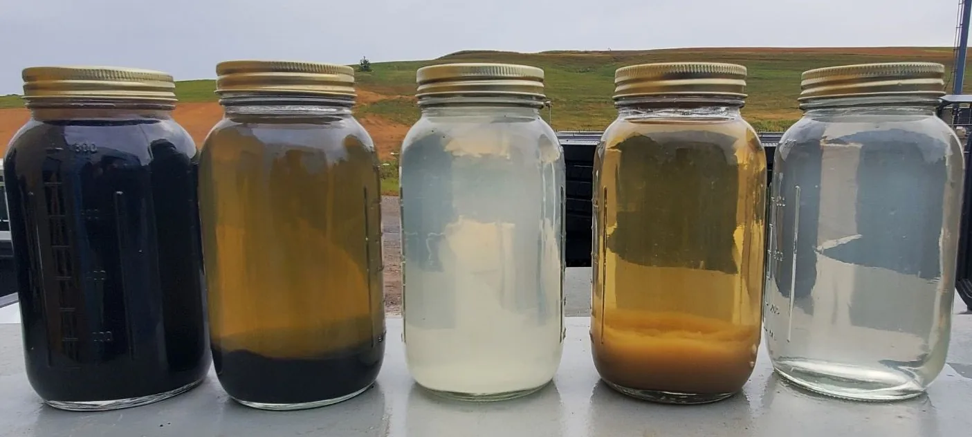 Five sample jars from a water treatment pilot test, showing the range of water quality