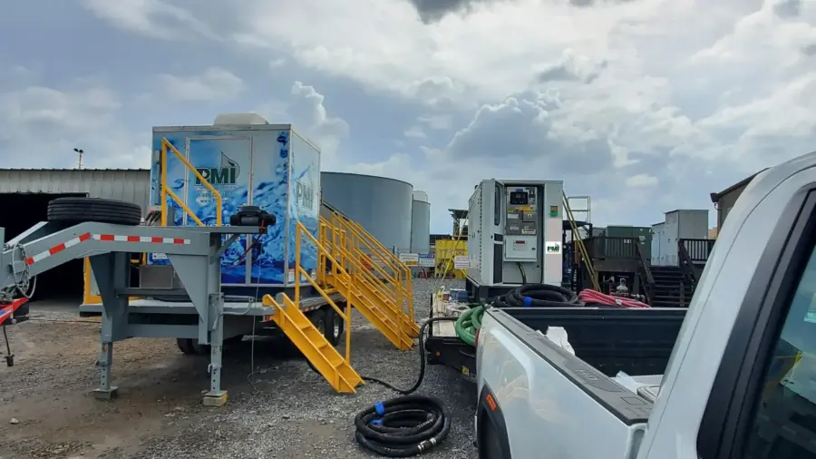 PMI EC-AOP water reclamation unit set up beside storage tanks on a job site